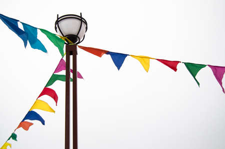 Festive triangular flags in the form of garlands hang tied to a lamppost. Decoration ideas in celebration of an event, isolated on a white background.の写真素材