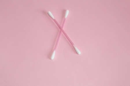 Top view, flat lay, two pink plastic cotton swabs arranged crosswise on a pink background, the concept of cleanliness and hygieneの写真素材