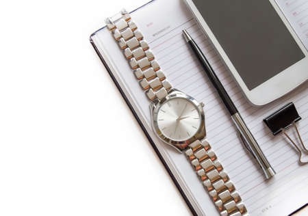 Office Desk with a diary, smartphone, pen on a Notepad, men's wrist watch. Top view with copy space on a white background.の写真素材