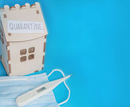 Medical mask, thermometer and wooden house and a piece of paper with the inscription QUARANTINE, the Concept of prevention of coronavirus disease.の写真素材