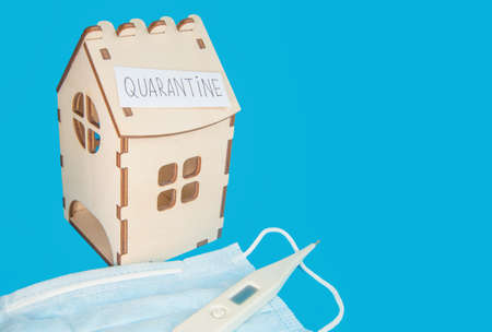 Medical mask, thermometer and wooden house and a piece of paper with the inscription QUARANTINE, the Concept of prevention of coronavirus disease.の写真素材