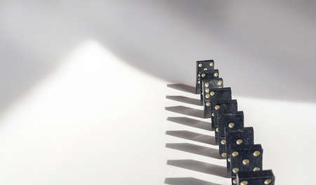 Black Domino in a line on a white background with shadows and small DOFの写真素材