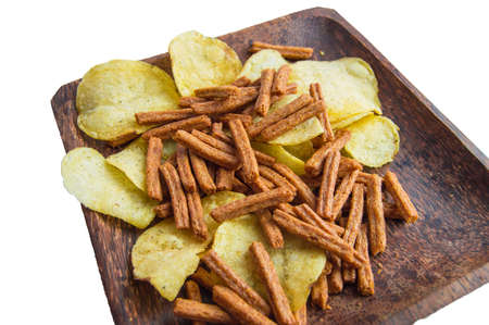 Delicious potato chips and salted rye bread crackers on a dark wooden plate, isolated on a white background by clipping.の写真素材