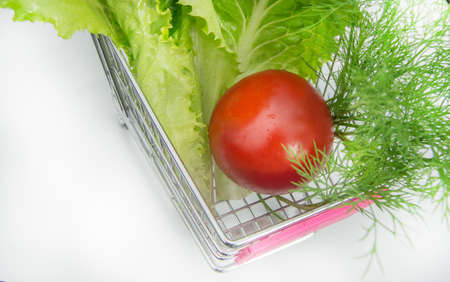 Basket full of various fresh vegetables tomato, lettuce, dill on a white background, top view.の写真素材