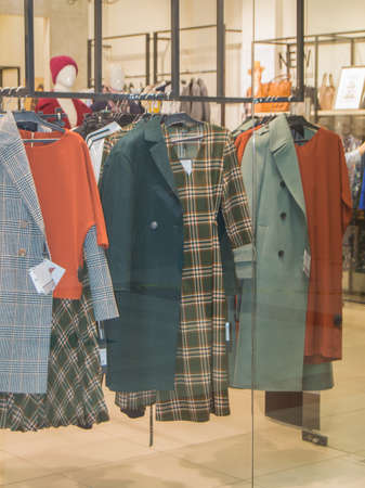 A collection of autumn casual outerwear hangs on hangers in a fashion store.の写真素材