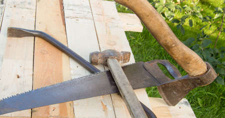 building tools hammer, axe, hacksaw frame, lie on the light boards in the garden