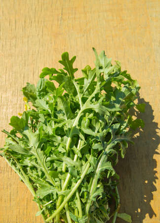 A bunch of fresh green arugula on a light wooden background, bright sunlight, top view, flatlayの写真素材