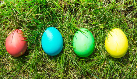 Four painted and decorative Easter eggs in the grass. Top view, copy space.