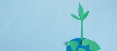 Cute children's paper applique -a model of the Earth and a young sprout on a blue background. Creative concept Earth Day, Earth Hour, copy space for text.の写真素材