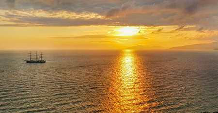 Romantic golden sunset on the sea with a yacht against the background of mountains and orange...