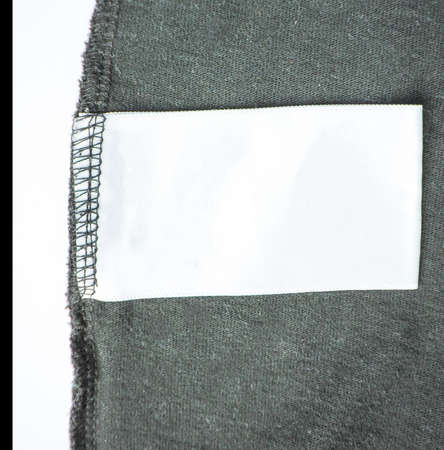 Empty empty clothing label for laundry information on the background of a black knitted jacket.
