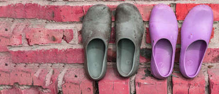 Two pairs of rubber galoshes in black and pink on the background of an old brick wall, a copy of the...