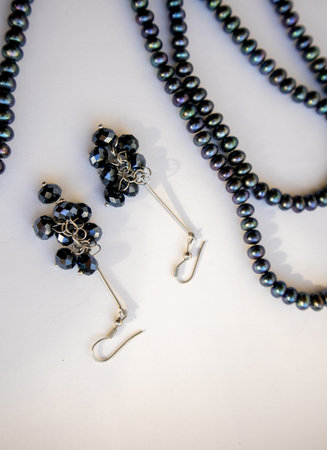 Black pearl beads and earrings on a light background, a beautiful set of jewelryの写真素材