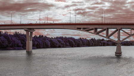 View of a large automobile bridge over a wide river against a cloudy sky.