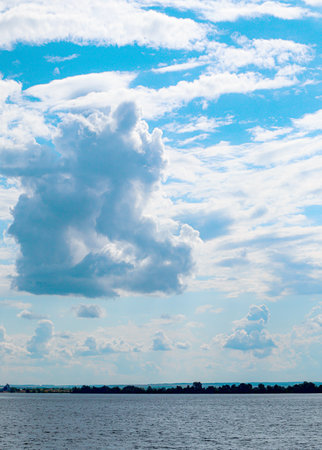 Vertical shot of beautiful cumulus clouds over the river, summer morningの写真素材