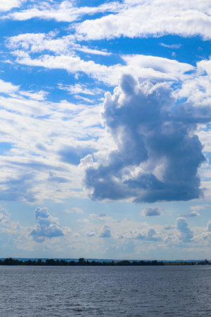 Vertical shot of beautiful cumulus clouds over the river, summer morningの写真素材
