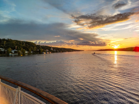 Golden sunset over the river, view from the motorboat on the calm water surface and houses on the shore, beautiful evening panorama.の写真素材