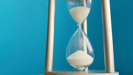 Close-up of hourglass on light blue background. Time and money saving concept.の写真素材