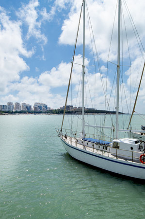 Vertical view from the pier of a yacht and the shoreline of a city beach with houses, sunrise in summer.の写真素材