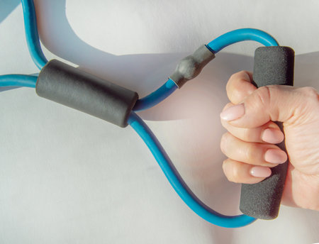 A woman's hand squeezes a rubber strength training expander, demonstrating arm exercises to improve...