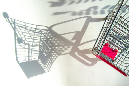 Shadow of a supermarket shopping cart on a white background with sunlight. Minimalist shopping conceptの写真素材
