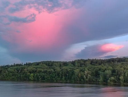 A beautiful pink sunset on a cloudy sky over the forest, along the bank of the Volga River in Russiaの写真素材