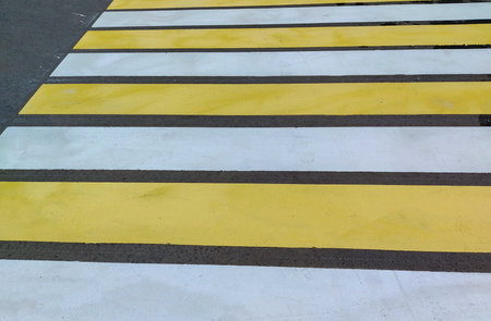 Close-up of the new yellow and white crosswalk markings on an asphalt road