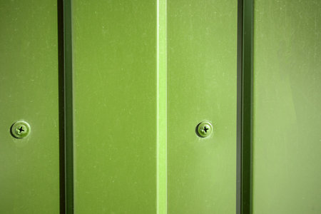 Green industrial background self-drilling in corrugated sheet close-up.