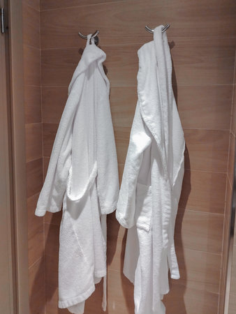 Two white robes on a rack in the hotel bathroom.の写真素材