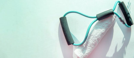A banner with fitness training accessories, a towel and a hand-held rubber expander in the sunshine.の写真素材