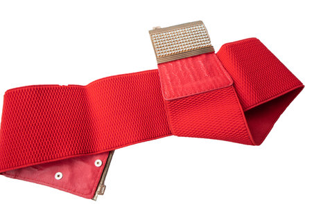 Red fashionable women's knitted elastic band belt with metal buckle with rhinestones, isolated on white background.の写真素材