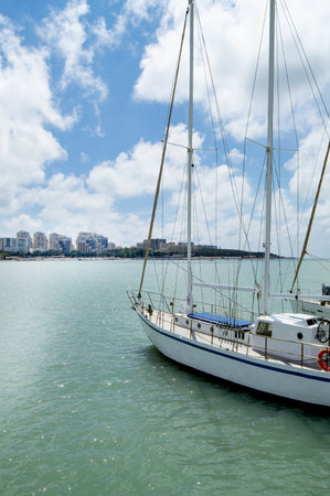 Vertical view from the pier of a luxury yacht and the shoreline of a city beach with houses, sunrise in summer.の写真素材