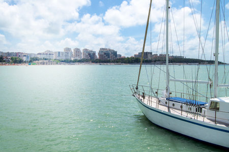 View from the pier of a luxury yacht and the shoreline of a city beach with houses, sunrise in summertime.の写真素材