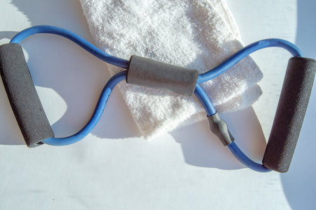 A banner with fitness training accessories, a towel and a hand-held rubber expander in the sunshine.の写真素材