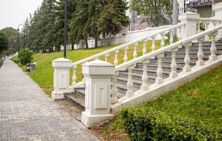 Vintage white stone staircase with balustrade against a grass-covered slope in a summer park, side view.の写真素材