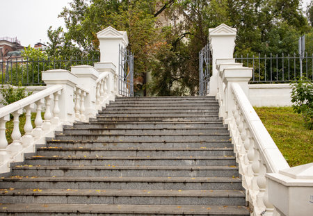 Elegant white stone staircase with balustrades, view from below of the parks open metal gatesの写真素材