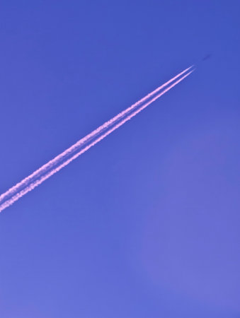 Jet airplane with contrails in clear sky, minimalism, vertical, social banner, vertical poster, mobile lock screenの写真素材