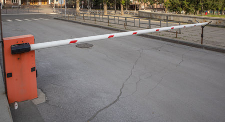 Red and white metal barrier, blocking the road, protecting the territory, controlling entry.
