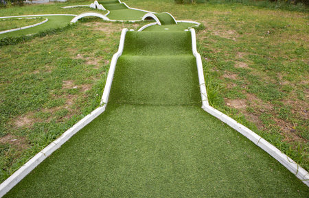 Mini golf course with artificial turf and ramps view of the hole and obstacles Clean background for family fun parks and entertainment ads with copy spaceの写真素材