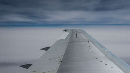 Airplane wing above the clouds, during a scheduled flightの写真素材