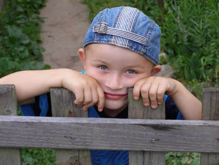 Little boy leaned against the fence の写真素材