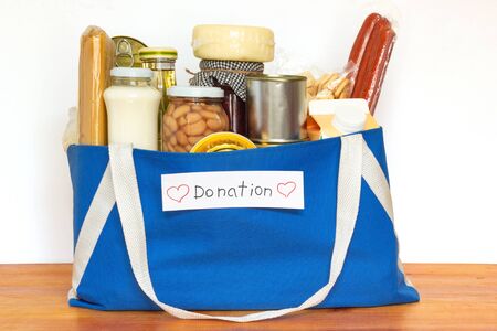 Set of grocery food for needy in crisis, pasta, beans, canned food, and others in blue shopping bag ready for donationの写真素材