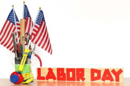 Bouquet of tools with US flags on a table and duct tape text on a board, concept of the patriotic holiday of labor dayの写真素材