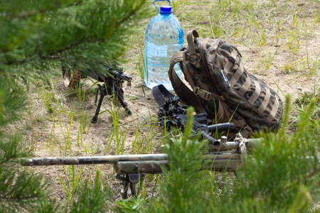 Three rifles, backpack and bottle of water on the ground in the forest, army weapon of active...