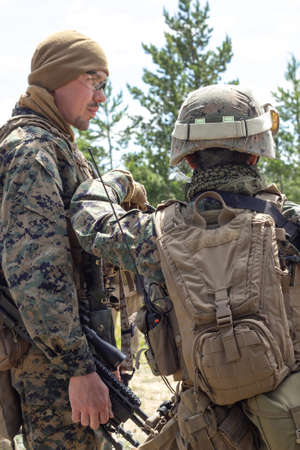 Two fully armed american soldiers in the summer forest on military range, active military game...