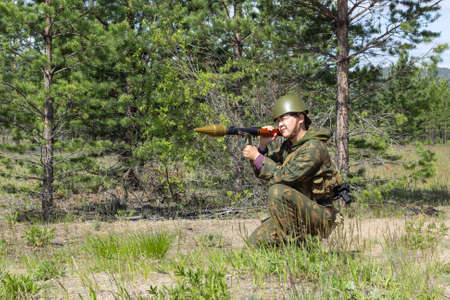 Fully armed asian soldier with bazooka takes aim for a shot in the summer forest, active military game airsoftの写真素材