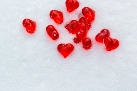 Set of small bright red glass hearts on powdery snow of snowdrift at cold winter day, symbol of romantic love, St. Valentine's Day holiday concept, top viewの写真素材