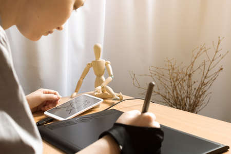 Woman sketching on phone with graphic tablet, scandinavian decor of dry branches reflects nordic lagom or kinfolk style, modern technology concept, neutral pastel colors and soft beige earth tonesの写真素材