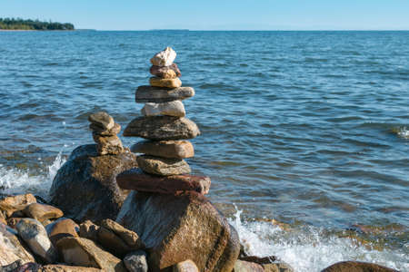 Close up two pyramids of stacked stones on a boulder on the inshore waves of Lake Baikal at summer sunny day, beautiful scenic seascape, stability, balance and harmony conceptの写真素材