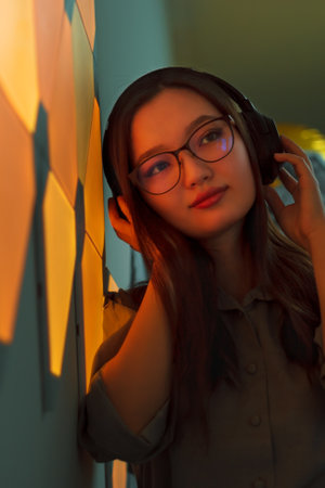 Young smiling woman with headphones in yellow neon light listen to music, nightclub futuristic neon...